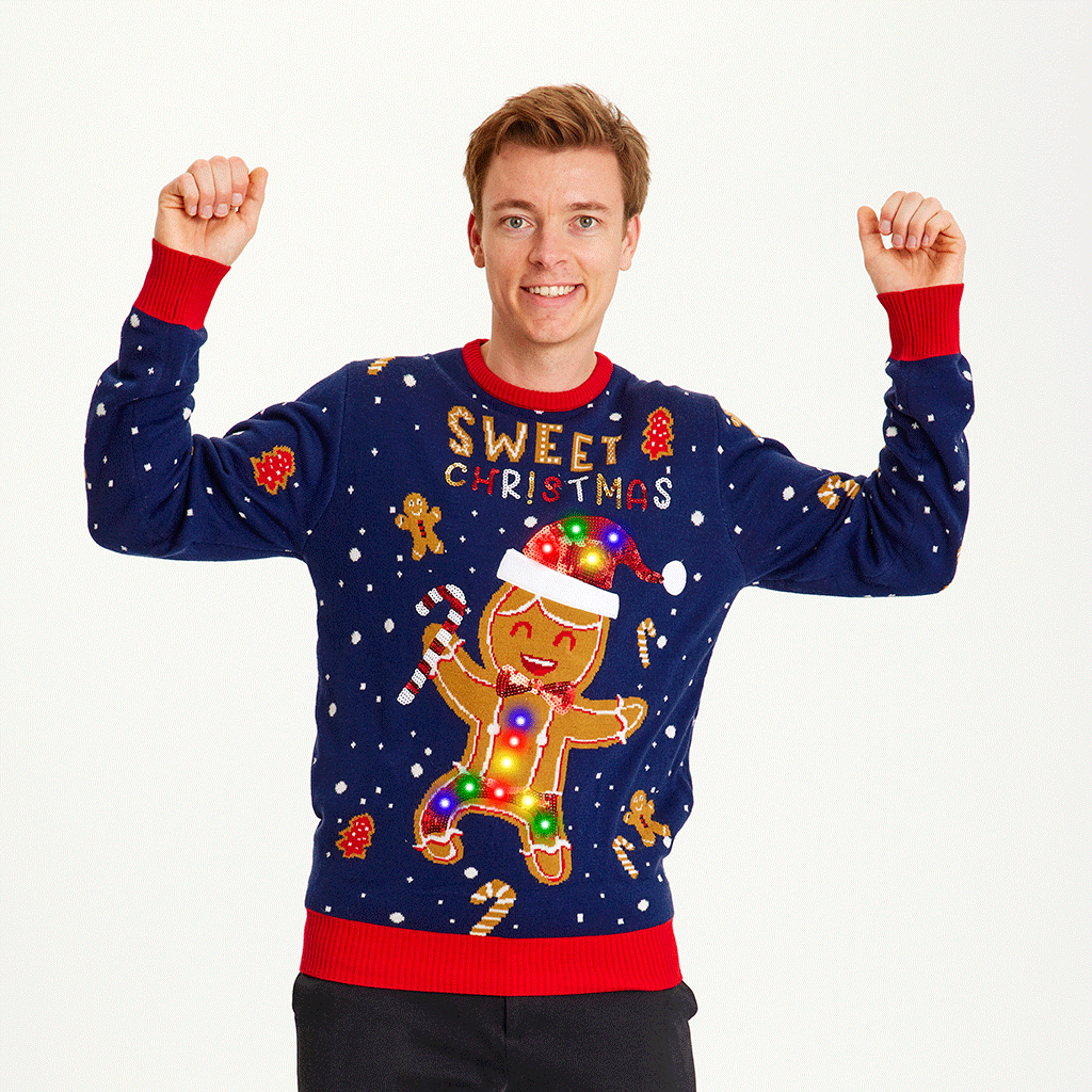 En glad mand med hænderne i vejret poserer med en blå julesweater med lys.